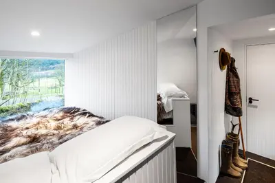 a bedroom with white walls and a bed with a window at Monachyle Mhor Hotel in Lochearnhead