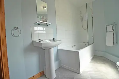 a white bathroom with a sink and a bath tub at The Clamshell, Oban in Oban