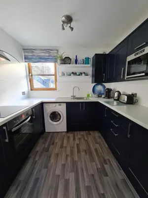 a kitchen with black cabinets and a washing machine at The Clamshell, Oban in Oban