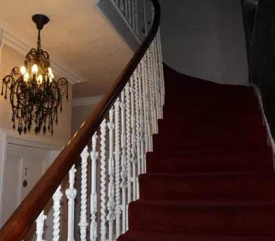 a staircase with a chandelier in a house at Arbour Guest House in Oban