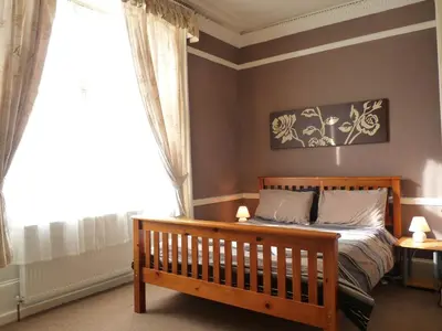 a bedroom with a wooden bed and a window at Arbour Guest House in Oban