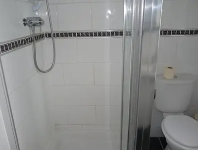 a white bathroom with a shower and a toilet at Arbour Guest House in Oban