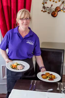 a woman is holding two plates of food at Craignelder Hotel in Stranraer