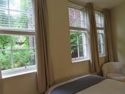 a bedroom with two windows and a bed and a chair at The cosy courtyard in Edinburgh