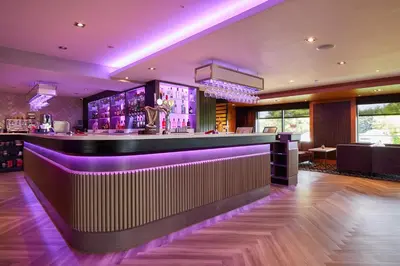 a bar in a restaurant with purple lighting at Lochside House Hotel & Spa in New Cumnock