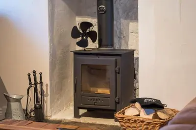 a wood stove in a room with a basket at Country Nest in Carnwath