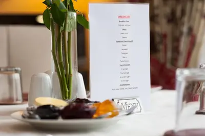 a table with a plate of food and a vase with a plant at Dean Park Guest House in Kilmarnock