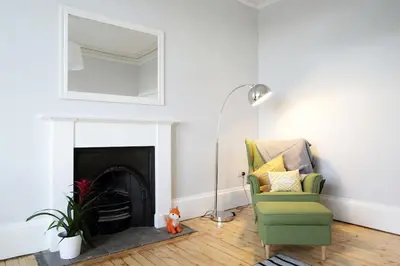 a living room with a green chair and a mirror at Stylish City Centre Apartments - D Terrace Residence in Edinburgh
