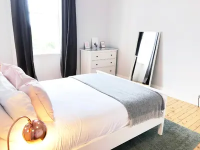 a bedroom with a white bed and a mirror at Stylish City Centre Apartments - D Terrace Residence in Edinburgh