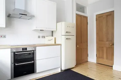 a kitchen with white appliances and a black and white refrigerator at Stylish City Centre Apartments - D Terrace Residence in Edinburgh