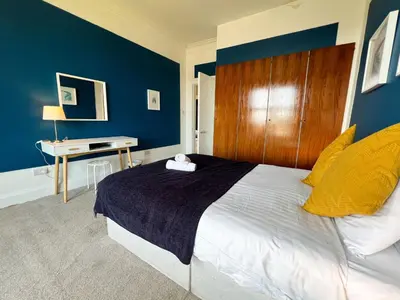 a bedroom with a large bed with a wooden headboard at A Spacious Flat with Character - Private Car Space in Paisley