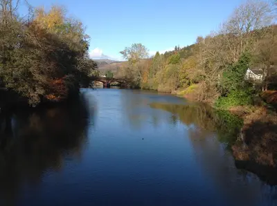 a view of a river with a bridge in the background at Riverbank in Callander