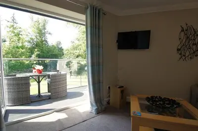 a living room with a large window with a view of a patio at Riverbank in Callander