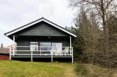a house with a balcony with two chairs on it at Heron Lodge sleeps up to 4 with free wifi in Crianlarich