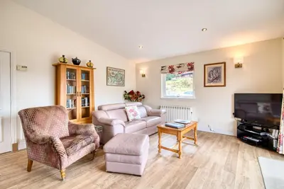 a living room with a couch chair and a tv at Kingfisher Lodge with sensational loch views in Crianlarich