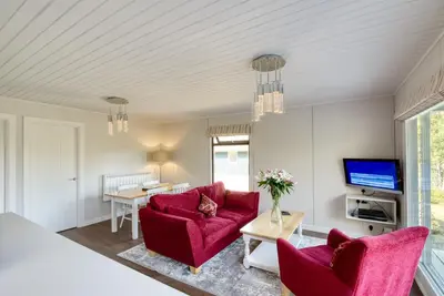 a living room with two red chairs and a tv at 2 bedroom lodge with stunning loch mountain views in Crianlarich
