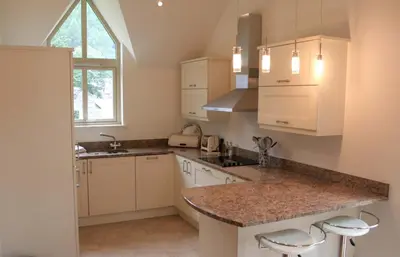 a kitchen with white cabinets and a granite counter top at Mains of Taymouth Country Estate 4* Houses in Kenmore