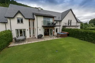 a white house with a lawn in front of it at Mains of Taymouth Country Estate 5* Houses in Kenmore