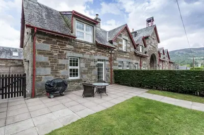 a brick house with a table and chairs in front of it at Mains of Taymouth Country Estate 5* Houses in Kenmore
