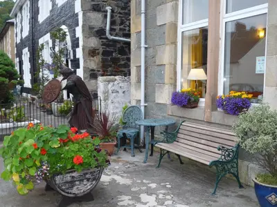 a statue of a woman standing next to a bench at St Annes Guest House in Oban