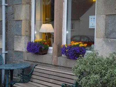 a bench sitting in front of a window with flowers at St Annes Guest House in Oban