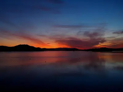 a sunset over a large body of water at The Inn on Loch Lomond in Luss