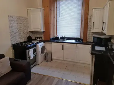 a kitchen with a sink and a stove and a microwave at Rozina Apartment in Paisley