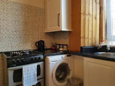 a kitchen with a stove and a washing machine at Rozina Apartment in Paisley