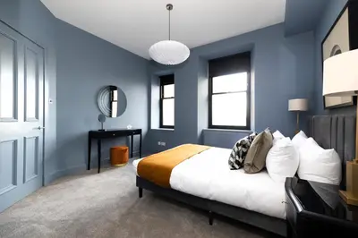 a blue bedroom with a bed and a desk at JOIVY Luxury Home on George Street in Edinburgh