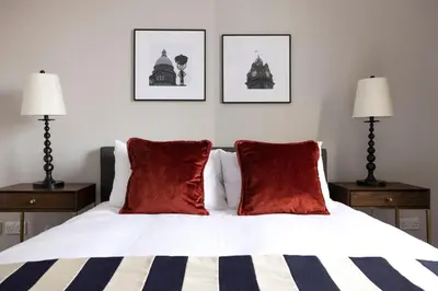 a bedroom with a bed with red pillows and two lamps at JOIVY Luxury Home on George Street in Edinburgh