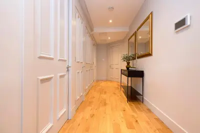 a hallway with white walls and wood floors and a mirror at JOIVY Luxury Home on George Street in Edinburgh