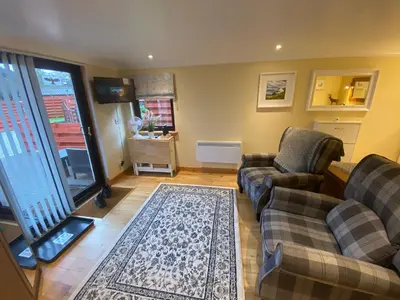 a living room with two couches and a rug at The Wee Ludging - A Cosy Riverside Cottage for Two in Dunoon