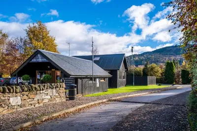 a building with a stone wall next to a road at Mains of Taymouth Country Estate 5* Gallops Apartments in Kenmore