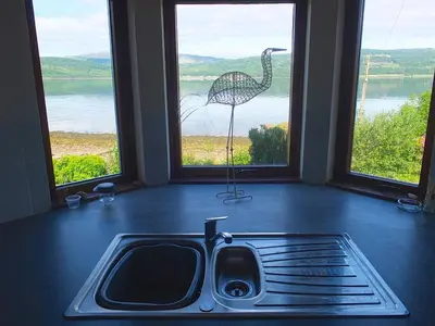 a kitchen with a sink and a bird in the window at Trefoil Holiday Home in Strachur