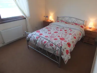 a bedroom with a bed with a floral bedspread at Trefoil Holiday Home in Strachur