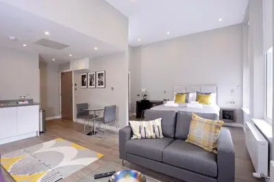 a bedroom with a bed and a couch and a kitchen at Nelson Mandela Place Apartments in Glasgow
