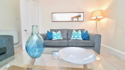 a living room with a couch and a glass table at Snug - Tùr Sealladh Apartment in Helensburgh