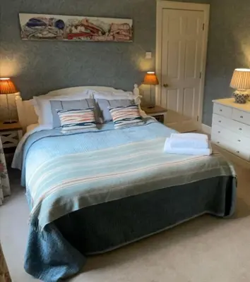 a bedroom with a large bed with blue sheets and pillows at River View Knockraich Farm in Fintry