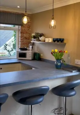 a kitchen with a counter with two blue bar stools at River View Knockraich Farm in Fintry