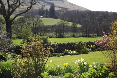 a garden with flowers and a hill in the background at River View Knockraich Farm in Fintry