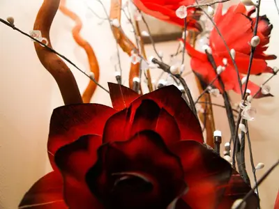 a vase filled with red flowers and branches at HLA - KING COURT APARTMENT 2 in Motherwell