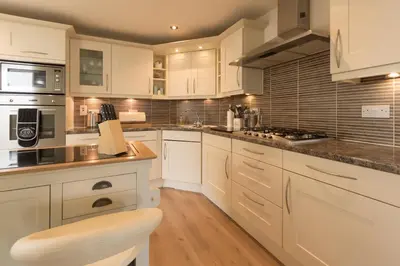 a kitchen with white cabinets and a stove top oven at Marina View Apartment in Inverkip