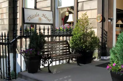 a bench in front of a store with flowers at Thistle Hotel in Edinburgh