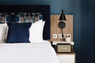 a bedroom with blue walls and a bed with a black headboard at Heeton Concept Aparthotel Edinburgh Queen Street in Edinburgh