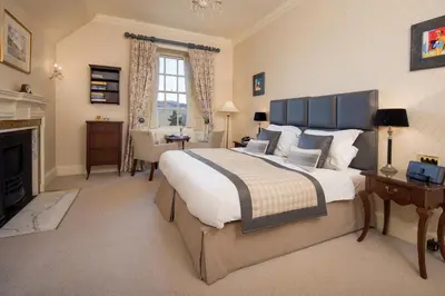 a bedroom with a large bed and a fireplace at Cringletie House in Peebles