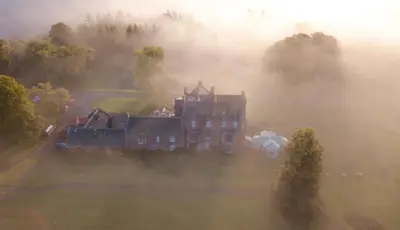 an aerial view of a castle in the fog at Cringletie House in Peebles