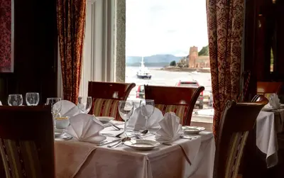 a table with glasses and napkins on it with a window at Columba Hotel in Oban