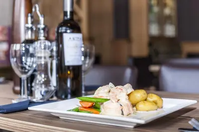 a plate of food on a table with a bottle of wine at Columba Hotel in Oban