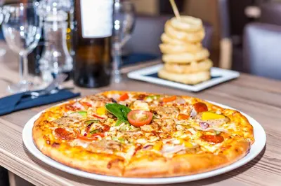 a pizza on a white plate on a table at Columba Hotel in Oban