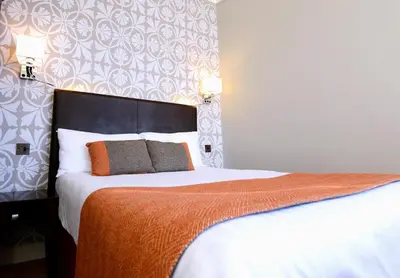 a bedroom with a large bed with an orange blanket at Columba Hotel in Oban